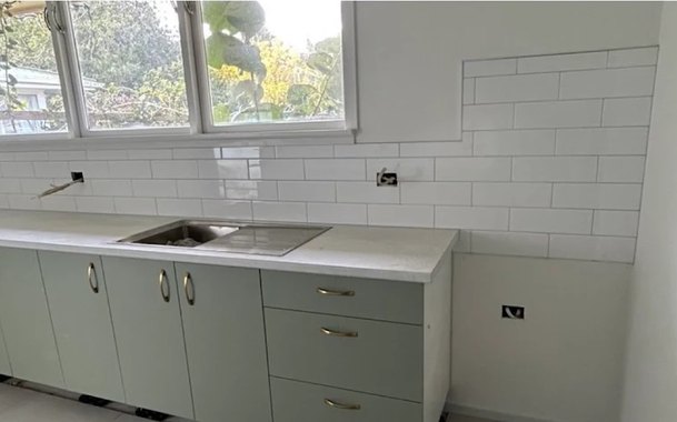 After: kitchen stripped back to bare plasterboard, then finished with white walls, subway tiles and sage cabinetry